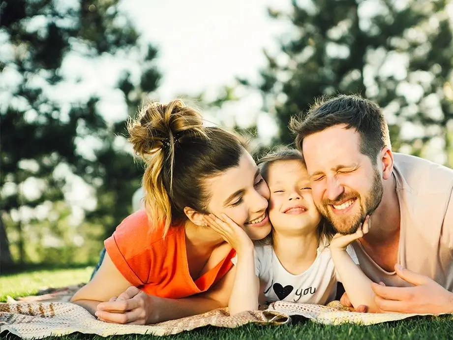 Smiling mother, father, and young daughter lying together on the grass
