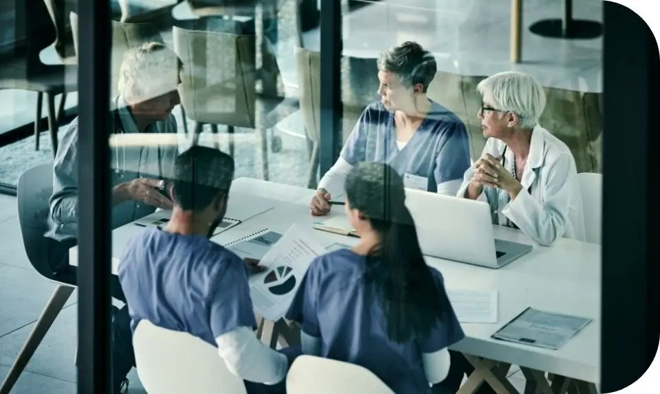 Dental team members reviewing patient charts around a conference table